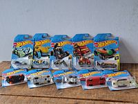 Overview photo showing 10 unopened Hot Wheels cars in their cards, arranged in two rows on a wooden surface.