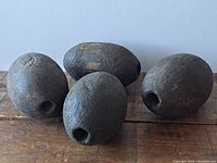 Four oval-shaped vintage wooden fishing net floats resting on a wooden surface with noticeable aged patina and wood grain.