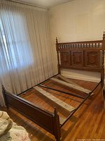 Full view of wooden bed frame including headboard, footboard, and metal support frame for mattress slats with two wooden slats resting inside the frame.