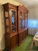 Full view of the wooden credenza with glass doors and carved details