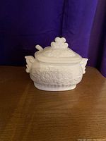 Front view of the porcelain gravy boat with floral design and attached lid.