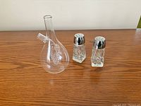 Clear glass oil/vinegar decanter and two crystal salt and pepper shakers displayed on wood surface.