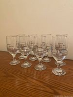 Photo showing seven Petro Canada Olympic glasses with plain rims arranged on a wooden surface.