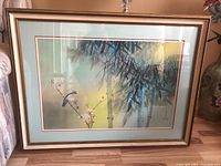 Full view of wood framed and matted art print with bird perched on blossoming branch and green bamboo background.