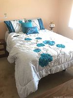 Bed with blue floral linens, including pillows and remote on bed surface