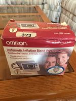 Image showing the original red box with Omron branding and product name 'Automatic Inflation Blood Pressure Monitor' with model number HEM-741CINT.