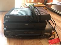 Front view showing stacked Panasonic Omnivision PV-8450 VHS player, RCA DVD player, and Dish Network VIP211z receiver with cables.