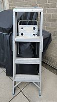 Front view of the 49 inch metal step ladder showing three wide step platforms, safety rail at the top, and blue rubber feet.