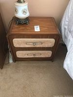 Full front view of wood nightstand showing fabric accent panels on drawers and metal handles.