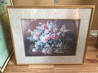 Framed floral print behind glass, showing entire frame and surrounding area.