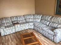 Wide view of the fabric sectional sofa arranged in an L-shape in a room with wooden floor and beige walls.