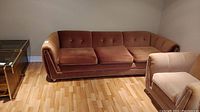 Full view of brown velour sofa with three cushions, wooden legs, and faded upholstery.