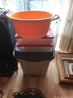 Stack of three storage totes with lids with an orange bucket on top