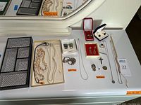 Overview of assorted jewelry items including necklaces, earrings, brooches, cufflinks, coins and valet tray.
