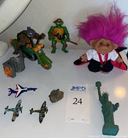 Full lot view showing TMNT figurines, pink troll doll, small planes, pyrite, and pheasant figurine