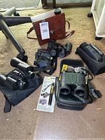 Full view of all optics including binoculars, night vision monocular, laser rangefinder, and cases.