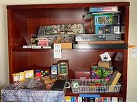Shelf containing all games and puzzles including chess set box and assorted brain teasers