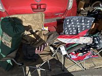 Five camping chairs including one with American flag design, golf umbrellas stored on chair seats, tote bag and flag also visible.