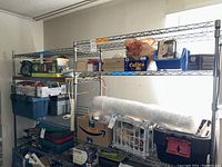 Overall view of two large connected chrome wire shelving units with various boxes and items on shelves