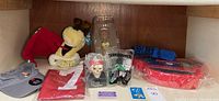Overall second image shows Odie Christmas stocking plush, gray adjustable men's hat, red 49ers signed apron, Transformers collectible figurine packaging, Disney Pirates accessory, Jack in the Box toy, and other small collectibles.