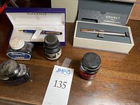 Overview of both boxed pens and four ink bottles on wood surface