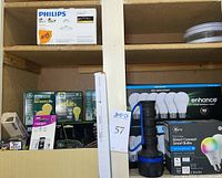 Shelf with Philips light therapy light box on top, various light bulb boxes below including GE and Halogen bulbs.