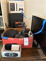 Lot overview showing PS2 console, PS2 box, DexDrive box, controllers and cables in Staples copy paper box next to ASUS monitor