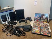 Overview of consoles, handheld, controllers, games and cables on floor