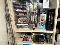 Multiple stacks of PS3 game cases on shelf including God of War Collection, Destiny, Battlefield, Red Dead Redemption.