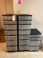 Pair of tall plastic drawer units each with 7 translucent drawers and black framing on caster wheels, beside a smaller 4-drawer Mini Chest unit with black top and frosted drawers. Units have some dirt and need cleaning.