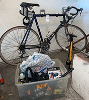 Full view of bike mounted on wall with clear bin of parts and floor pump visible