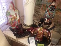 Photo of five Asian figurines arranged on a small table including ceramic and wooden pieces