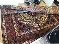 Partial top view of rolled carpet showing central medallion and border pattern