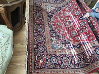 Whole carpet laid out on hardwood floor with partially rolled edge