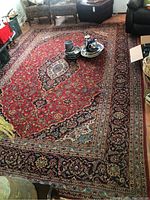 Full view of red oriental style area rug in room with furniture and decorative items on surface