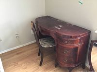 Side view of wooden dressing table and upholstered chair against wall