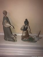 Two Lladro figurines on a mantle showing overall appearance and relative size