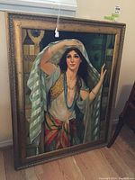 Full view of large framed painting of a woman in a striped veil and colorful attire.