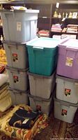 Stack of 68L Rubbermaid storage bins in gray, teal, and purple, showing different angles and arrangement of lids and handles.