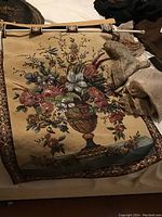 Full view of the hanging floral beaded tapestry showing the rod and part of assorted beaded linens.