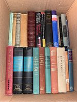 Box of multiple classic hardcover books arranged upright showing titles and wear of spines.