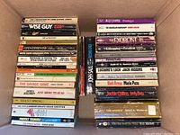 Top view of one box of paperback books showing titles like 'Wise Guy', 'The Savage Game', and 'The Exorcist'.