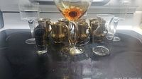 Full set of 12 cups and glasses including espresso cups, wine glasses, decanter, shot glass, and goblet arranged on a dark surface