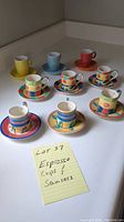 Overview of nine colorful espresso cups and saucers on a white surface with a sticky note reading 'Lot 37 Espresso Cups & Saucers'.