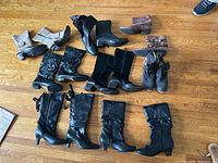 All 8 pairs of ladies boots arranged on wood floor, showing different styles and colors.