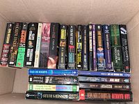 Top view of paperback books arranged upright in a box showing spines with titles mostly from mystery and crime genres including authors Michael Connelly, Joseph Finder, Allan Guthrie, Peter Robinson, and others.