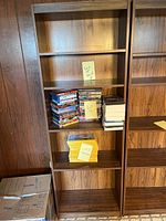 Photo of wooden shelving unit with DVDs and paper items on some shelves, showing scratches and wear on the wood finish.