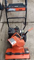 Front view showing the control panel with Ariens 520 branding and orange chute with engine details.