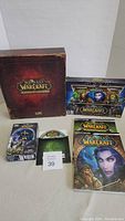 Photo showing a large decorative World of Warcraft Mists of Pandaria Collector's Edition box with artwork, a sealed Battle Chest Video Game Set, two gaming/strategy guides with distinct covers, and an additional game DVD disk.
