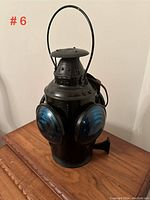 Black tail end marker lantern with three green and one red lens, metal handle and vented top.